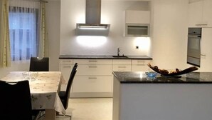 Ett modernt kök med vita skåp, en köksö och infällda taklampor.