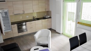 Un espacio habitable compacto con kitchenette, comedor y sala de estar con sofá y mesa.
