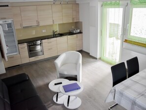 Ein kompakter Wohnbereich mit Küchenzeile, Essbereich und einer Sitzecke mit Sofa und Tisch.