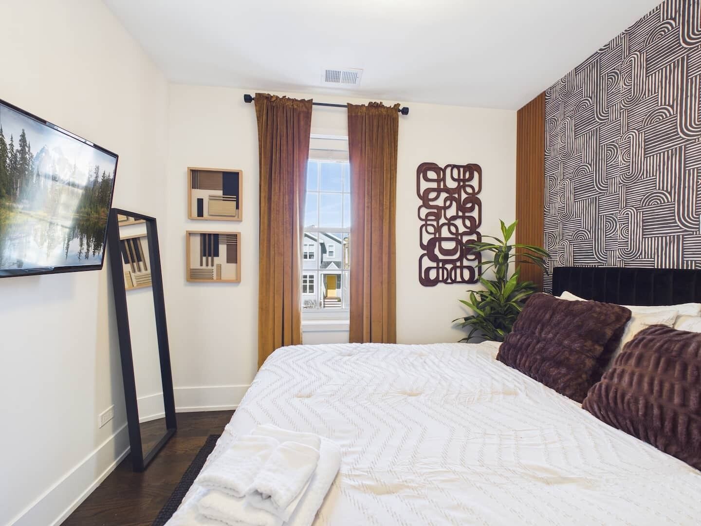 Une chambre d’hôtel avec un lit, une fenêtre avec des rideaux, une œuvre d’art accrochée au mur et un motif décoratif sur le mur.