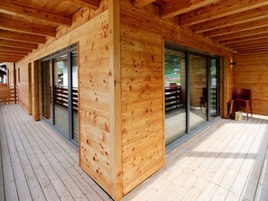 A wooden cabin with large sliding glass doors, a deck, and a covered outdoor area. - Derby Appartement/Fewo Derby 2 by Interhome (Saas-Fee)