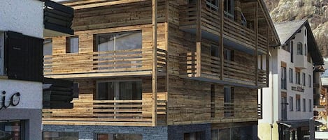 Un immeuble en bois à plusieurs étages, doté de balcons, de grandes fenêtres et d’une fondation en pierre.