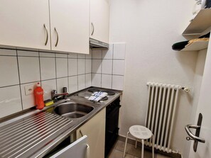 Eine kleine Küche mit Spüle, Herd und einem Hocker.