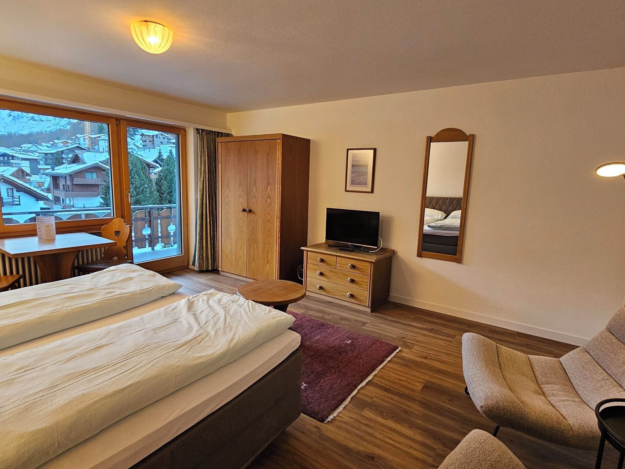 Ein Hotelzimmer mit Bett, Fernseher, Schreibtisch und Stuhl.