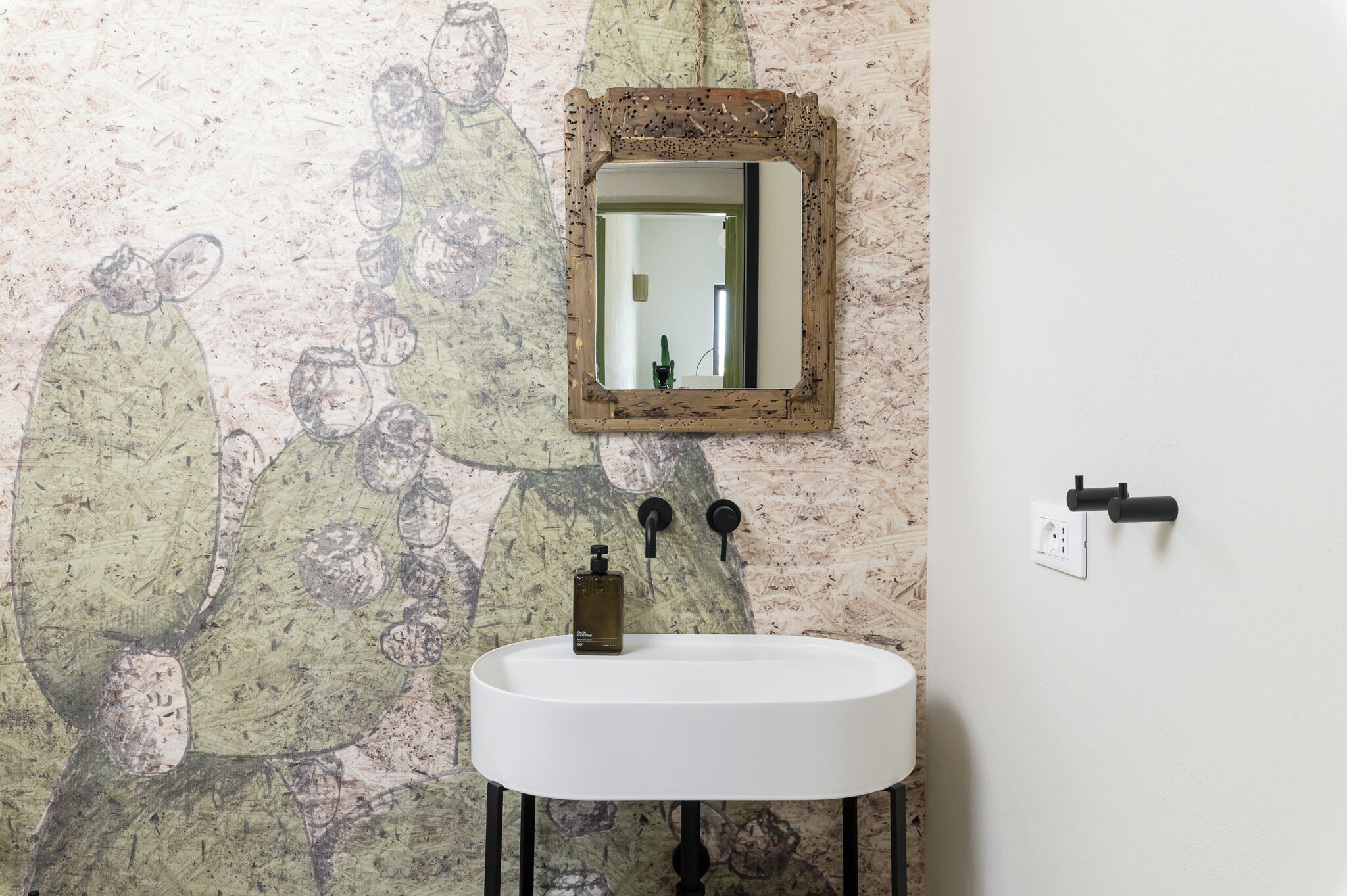 Un baño con un lavabo blanco, un espejo y una pared con textura.
