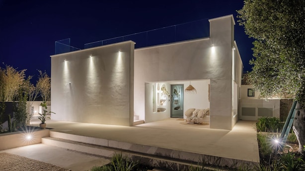 Una casa moderna con techo plano, un porche cubierto y una entrada bien iluminada.