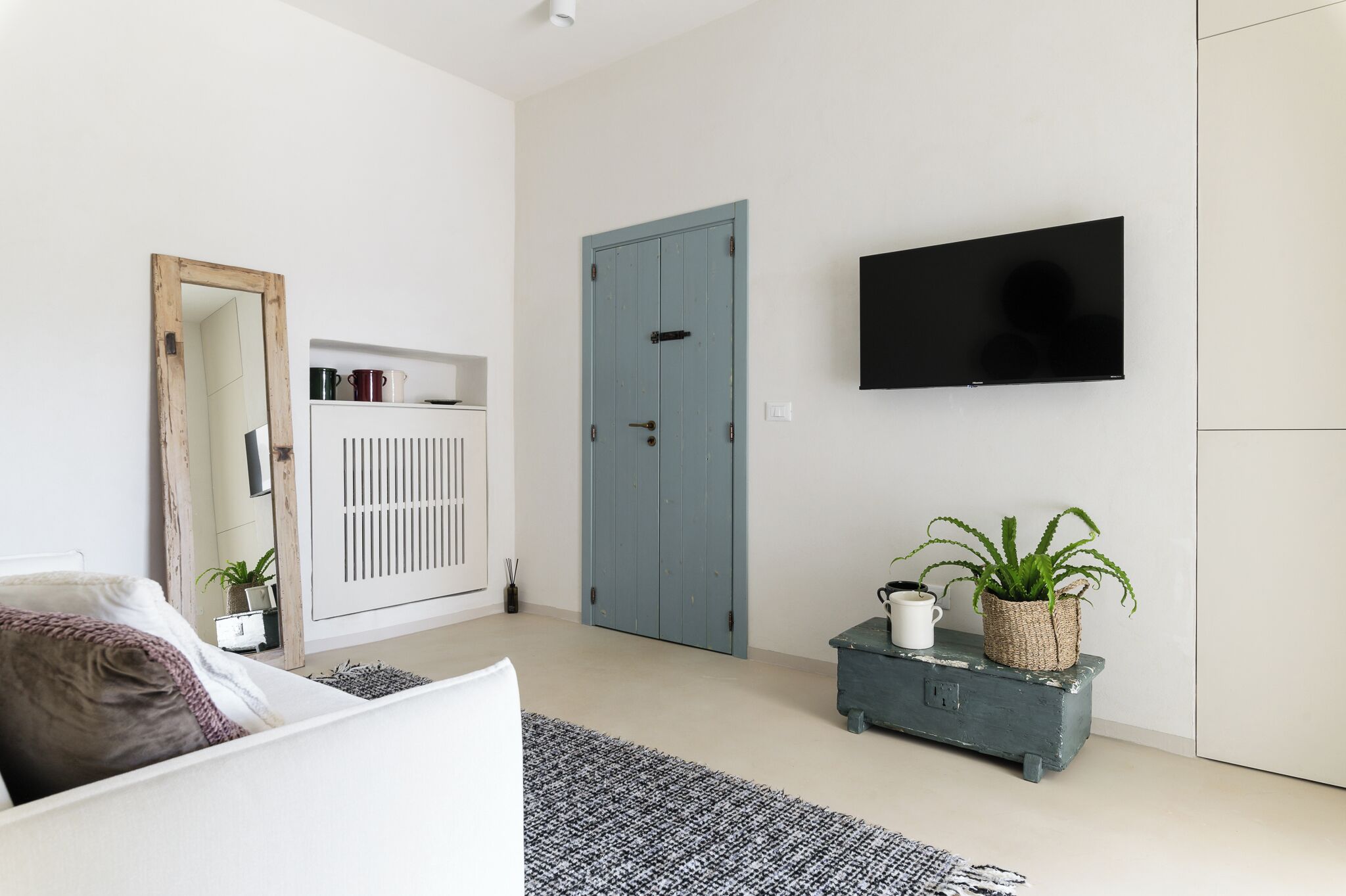 Een moderne slaapkamer met een bed, een kledingkast, een televisie en een plantentafel.