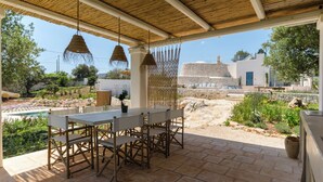 Un patio al aire libre con mesa y sillas, una piscina y un muro de piedra.