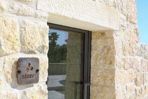 Un muro de piedra con una placa metálica que dice 'piedra' y una puerta de cristal.