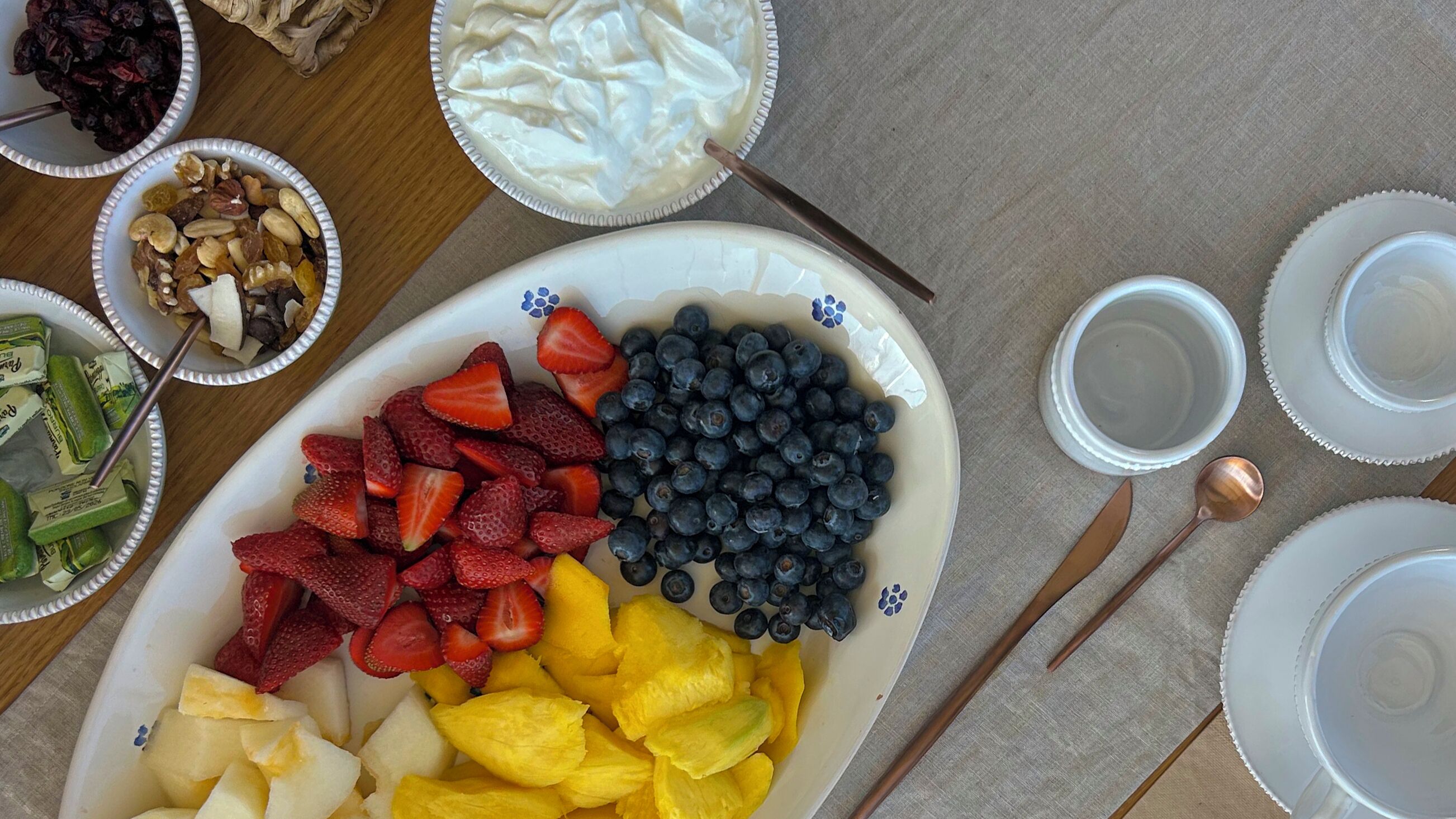 A plate of assorted fruits and a bowl of yogurt.