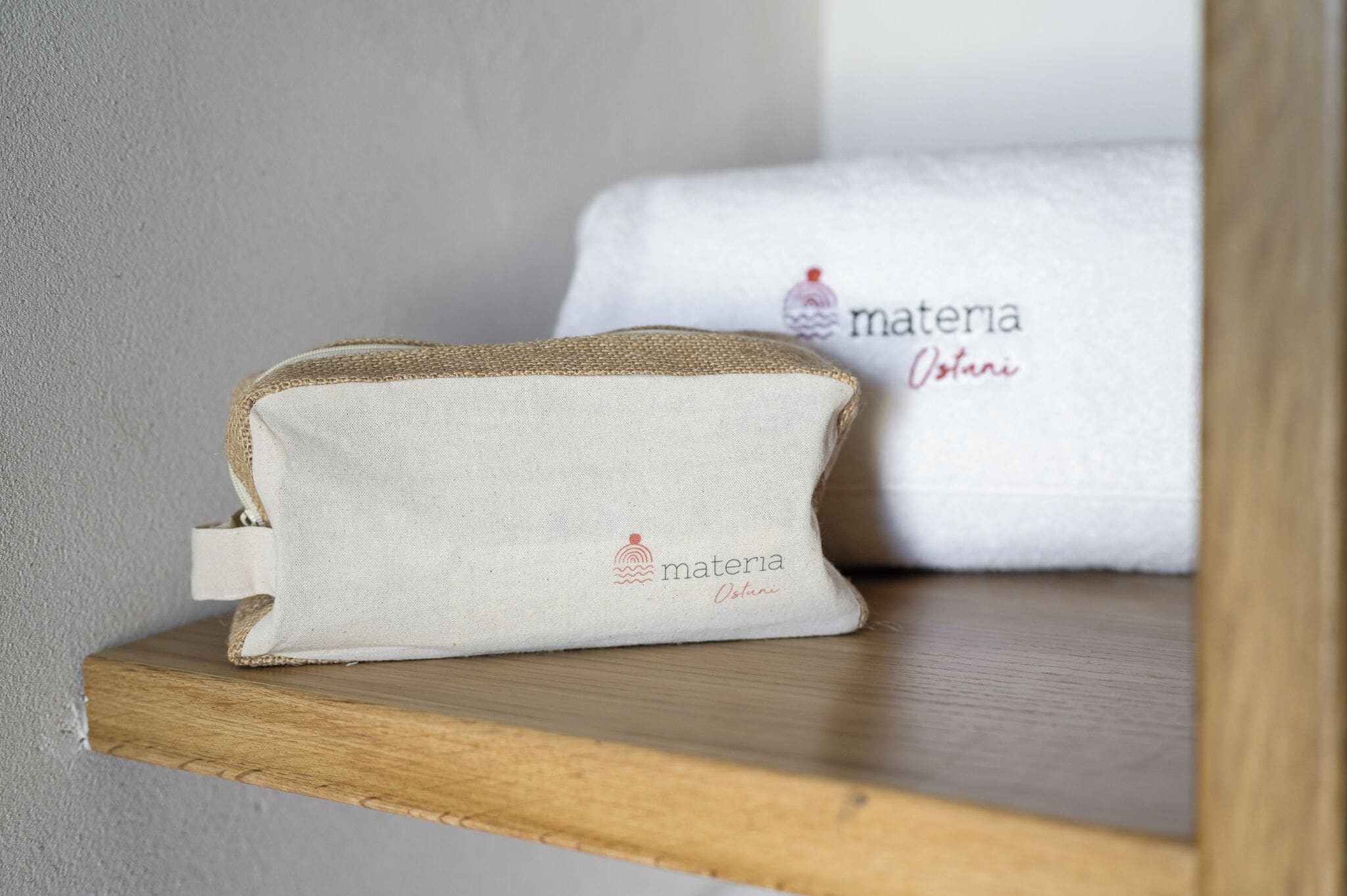 Una pequeña bolsa de tela blanca con un logotipo sobre un estante de madera.