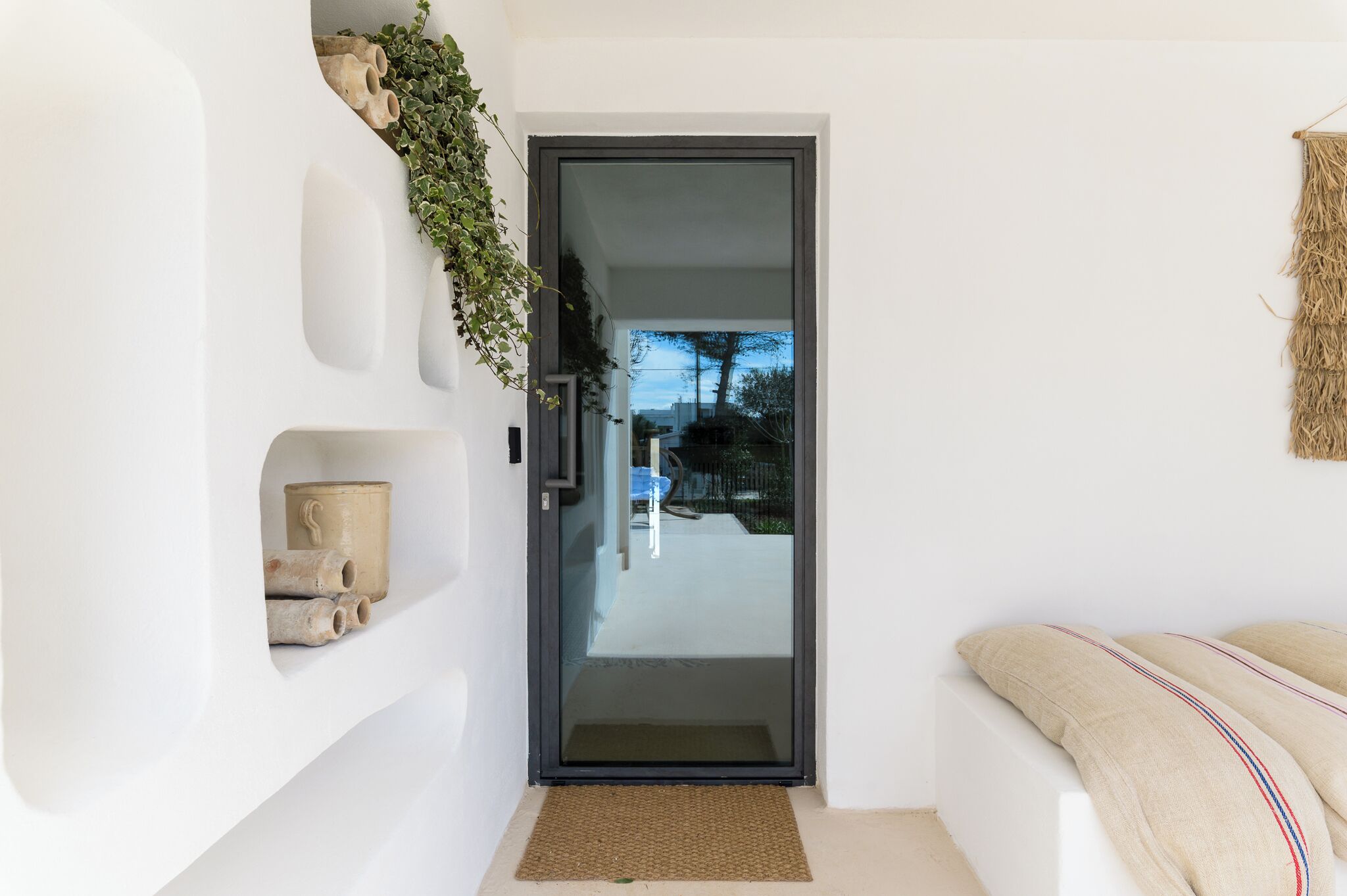 Ein modernes Interieur mit Glastür zu einem Balkon, weißen Wänden und einer gewebten Wanddekoration.
