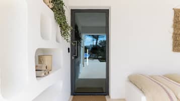 Ein modernes Interieur mit Glastür zu einem Balkon, weißen Wänden und einer gewebten Wanddekoration.