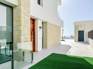 A modern building with a stone facade, a wooden door, and a glass entrance. - Luxurious villa with ocean views near Benidorm for 6 to 8 people (Finestrat)