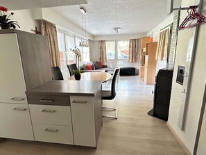 Un espacio habitable compacto con kitchenette, comedor y una pequeña zona de estar.