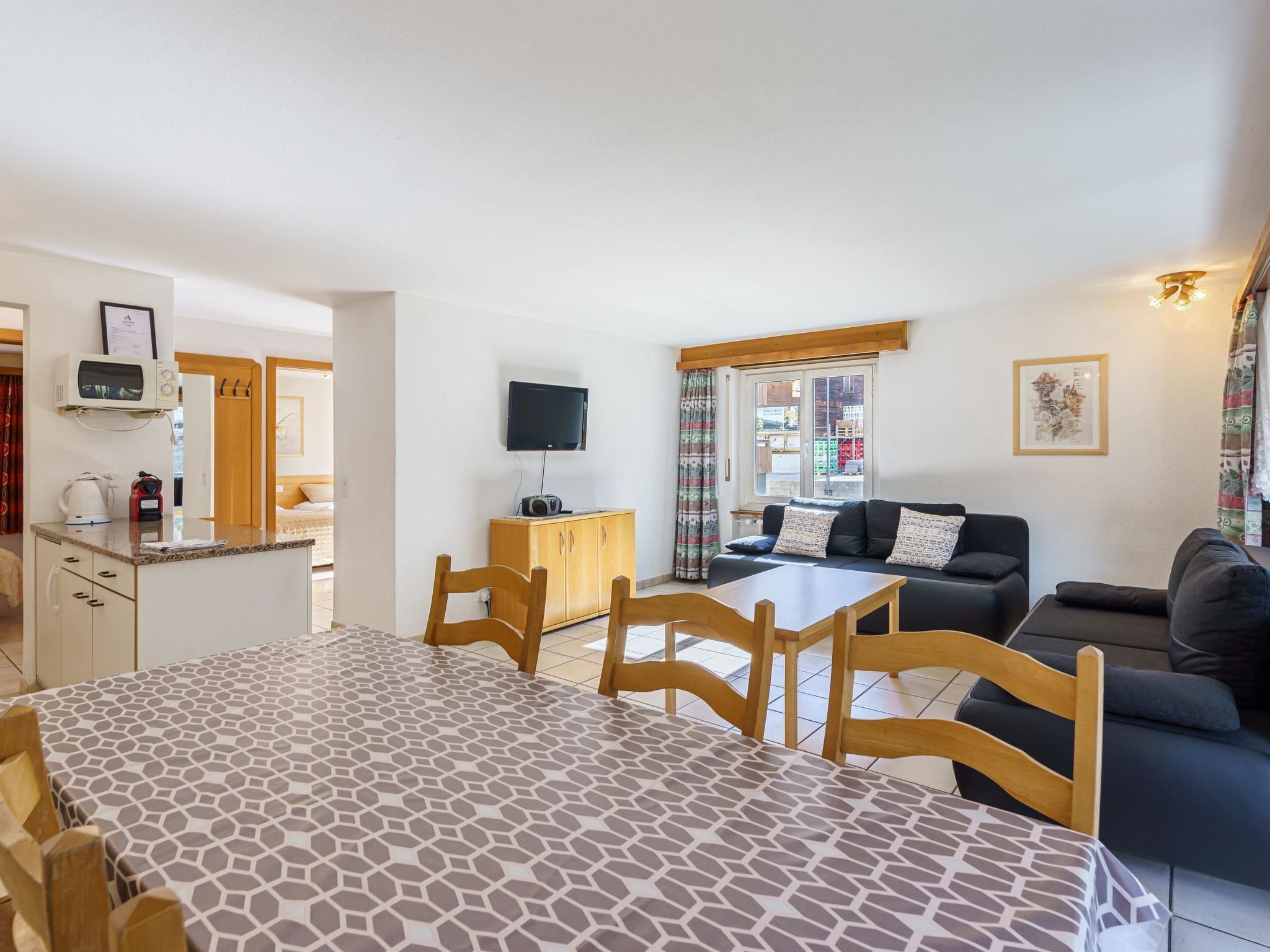 Ein modernes Apartment mit Essbereich, einem Wohnzimmer mit Sofa, einer Küche mit Mikrowelle und einem Fernseher.