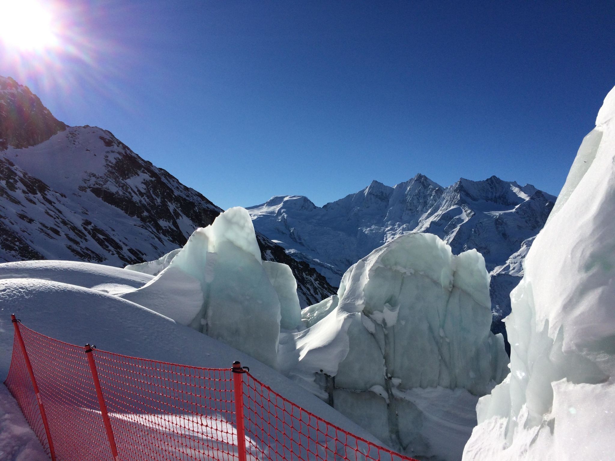 A snowy mountain landscape with a clear sky and a red safety net.