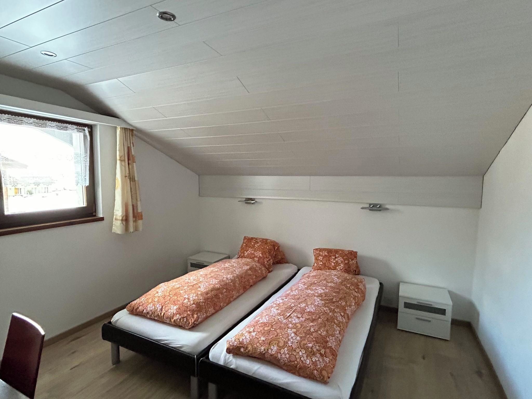 Un dormitorio pequeño y individual con dos camas individuales, un escritorio y una silla.