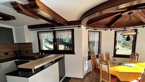 A modern kitchen with a central island, wooden dining table with chairs, and large windows with curtains. - Sunstar Appartement/Fewo 8-Bettwohnung Nr. 41 by Interhome (Saas-Grund)
