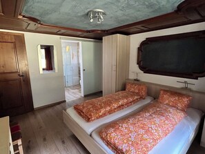 A bedroom with two beds, a wooden door, a small window, and a ceiling light fixture. - Sunstar Appartement/Fewo 8-Bettwohnung Nr. 41 by Interhome (Saas-Grund)