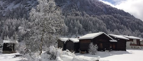 Una cabaña nevada con cabañas de madera, rodeada por un bosque y una montaña.