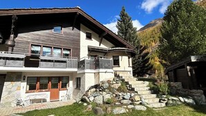 A two-story chalet with a stone facade, wooden balconies, and a stone staircase leading to the entrance. - Sunstar Appartement/Fewo 8-Bettwohnung Nr. 41 by Interhome (Saas-Grund)