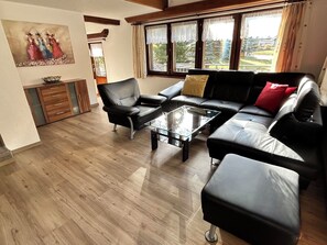 A living room with a black leather sofa, a glass coffee table, and a wooden cabinet. - Sunstar Appartement/Fewo 8-Bettwohnung Nr. 41 by Interhome (Saas-Grund)