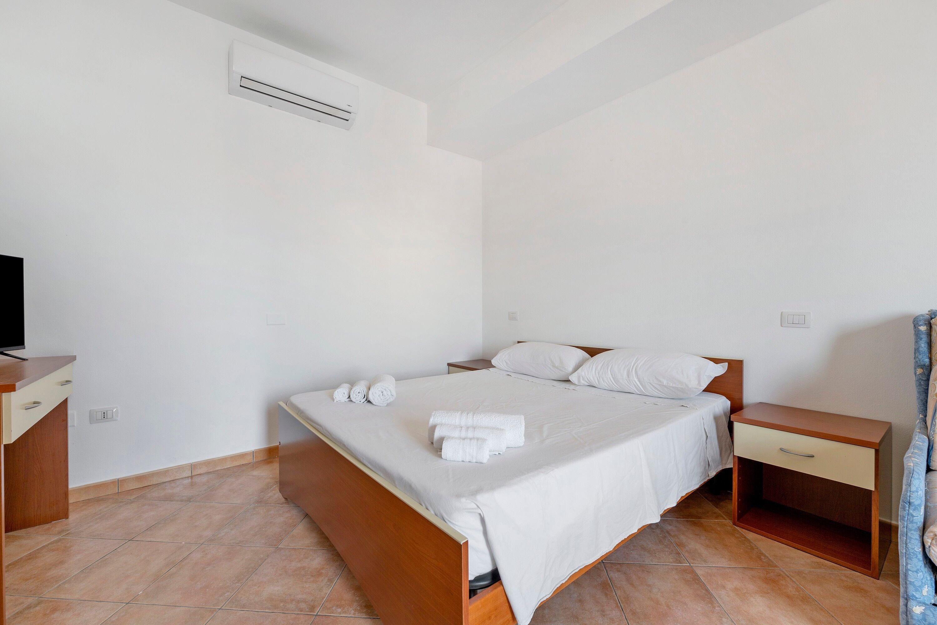 Een hotelkamer met een bed, een nachtkastje, een televisie en een badkamer met douchegordijn.