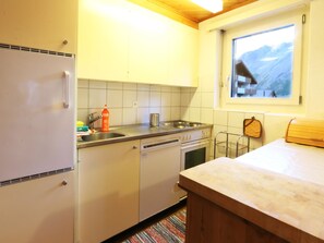 Uma cozinha com armários brancos, uma pia de aço inoxidável, uma lava-louças e uma janela com vista para montanhas.