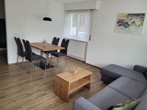 A modern living room with a wooden dining table, black chairs, a grey sofa, and a coffee table. - Haus Perle Appartement/Fewo 3-Bettwohnung Nr. 2 by Interhome (Saas-Fee)
