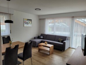 A modern living room with a grey sofa, wooden coffee table, and black chairs. - Haus Perle Appartement/Fewo 3-Bettwohnung Nr. 2 by Interhome (Saas-Fee)
