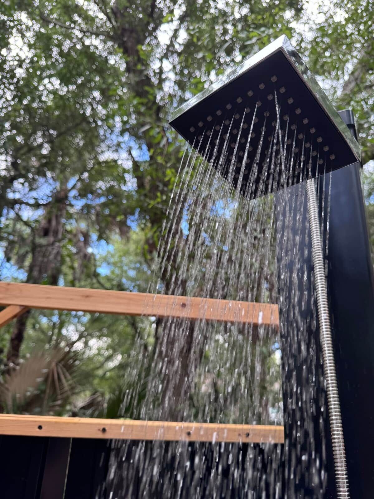 Un pommeau de douche d’où l’eau s’écoule sur une structure en bois.