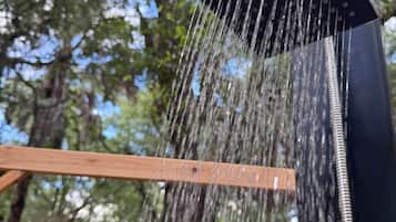 Un pommeau de douche d’où l’eau s’écoule sur une structure en bois.
