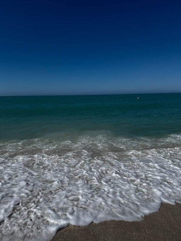 A beach with clear water and a visible horizon.