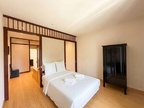 Een hotelkamer met een bed, een kledingkast en een schuifdeur die naar een andere kamer leidt.