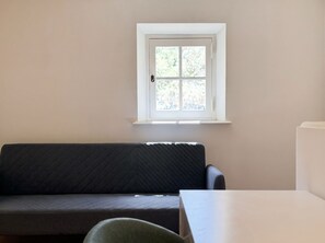 Een kamer met een raam, een bank en een tafel.