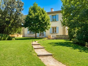 A two-story house with a stone facade, a well-maintained lawn, and a pathway leading to the entrance. - Provence Bastide XVIIIe Moderne, Calme, 10mn d'Aix - Ste-Victoire (Vauvenargues)