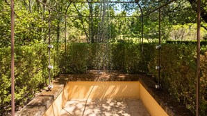 Eine Pergola aus Metall mit Wasserspiel in einem Garten.