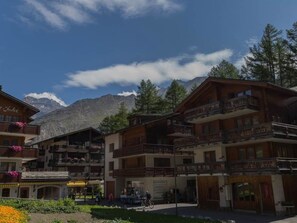 Eine Berghütte mit mehreren Balkonen, einer Skiseite und freiem Blick auf die Berge.