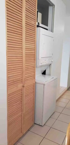 A laundry room with a white washing machine and dryer, a wooden closet, and a tiled floor. - Spacious 3BR steps to Beach- Family friendly (San Juan)