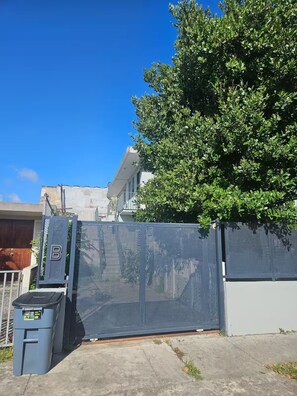 A gated entrance with a metal fence, a trash bin, and a tree. - Spacious 3BR steps to Beach- Family friendly (San Juan)