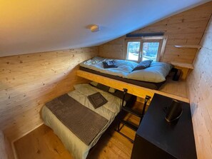 Ein kleines Zimmer mit Etagenbett, Schreibtisch und Fenster.