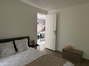 A bedroom with a bed, bedside table, and a bench. - 1-Bedroom Apartment in the Heart of Evreux (Évreux)