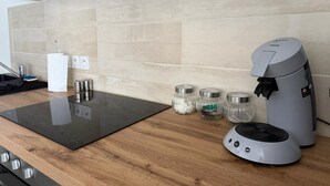 Eine moderne Küche mit eingebautem Herd, einer Kaffeemaschine und Gewürzgläsern auf der Arbeitsplatte.