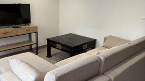 Ein modernes Wohnzimmer mit einer Couch, einem Couchtisch und einem Fernseher auf einem Lowboard.
