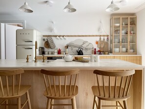 A modern kitchen with a marble island, wooden chairs, and a built-in cabinet with glass doors. - Sonnenhof Juliet Appartement/Fewo Appartement/Fewo by Interhome (Saas-Fee)