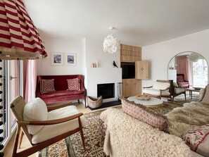 A living room with a red sofa, a white armchair, a patterned rug, and a fireplace. - Sonnenhof Juliet Appartement/Fewo Appartement/Fewo by Interhome (Saas-Fee)