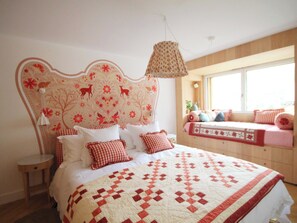 Ein Schlafzimmer mit einem großen Bett, einem Blumenmuster-Kopfende und einem Fenster mit Blick.
