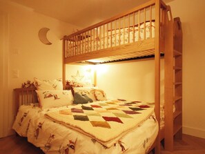 A bunk bed with a wooden frame, a quilt with a geometric pattern, and a crescent moon decoration on the wall. - Sonnenhof Juliet Appartement/Fewo Appartement/Fewo by Interhome (Saas-Fee)