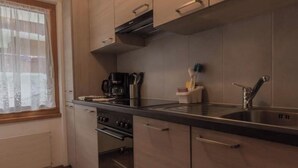 A modern kitchen with a stove, oven, sink, and wooden cabinets. - Bergfink Appartement/Fewo 4-Bettwohnung Nr. 3 by Interhome (Saas-Fee)
